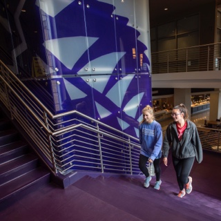 Two girls walk up a staircase in the multi purpose building at TCU's Worth Hills