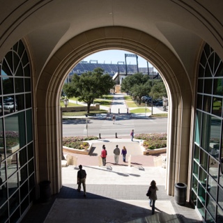 TCU students walk through the University Union arch with the football stadium in the background