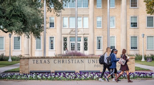 Three students walking in front of the Texas Christian University sign