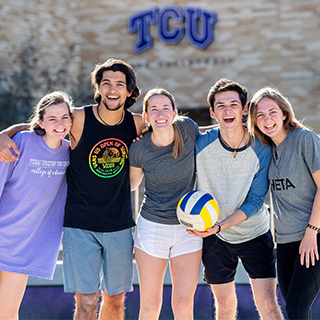 Five TCU students on the sand volleyball court